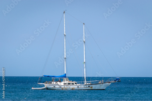 Old white yacht sailing the calm ocean on sunny day in the Caribbean