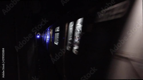 Loop of subway moving through dark tunnel. Loopable New York City inside subway tunnel with blue traffic signal light. Blurry train moves through underground railway in restricted area for people.