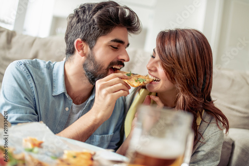 Happy young couple enjoying pizza at home