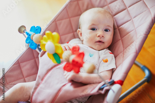 Baby girl playing with toys in bouncer photo