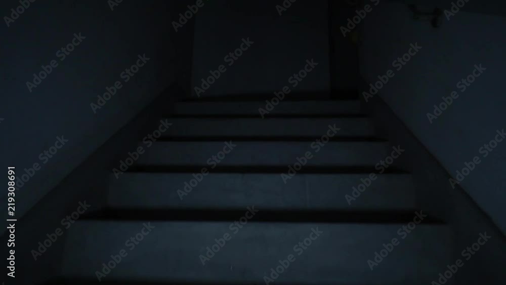 Climbing spooky stairs in darkness. Going up dark and dangerous stairs