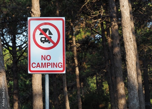 No camping sign among the trees, with the symbol of ban on camper and tent.