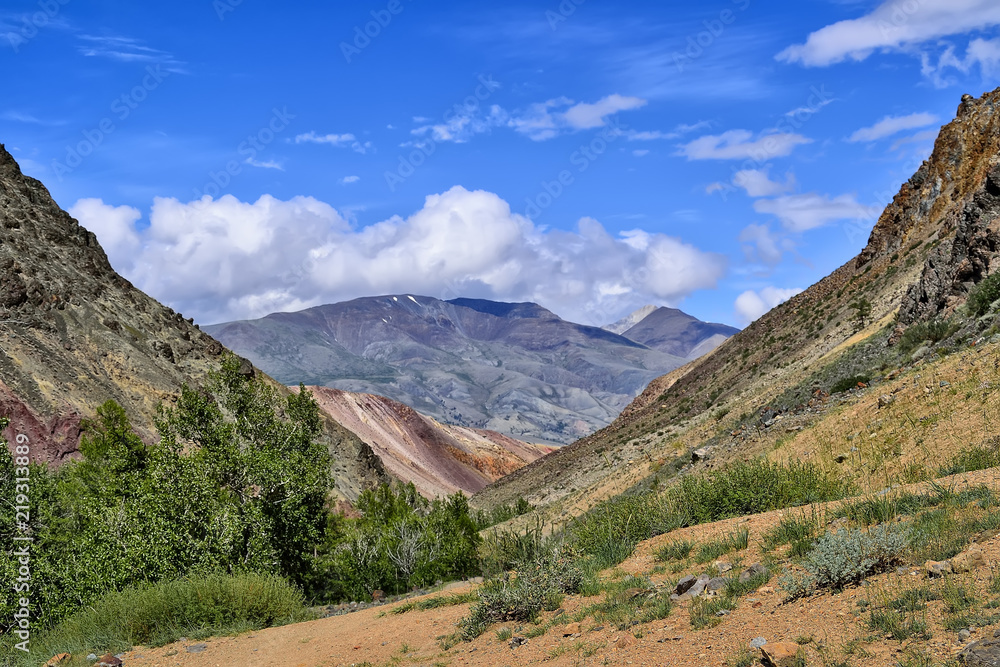Picturesque summer mountain landscape - view from the canyon of Kyzyl Chin with multicolored clay cliffs to the Kuray Range, Altai mountains, Russia. Beauty of wild nature Picturesque summer mountain landscape - view from the canyon of Kyzyl Chin with multicolored clay cliffs to the Kuray Range, Altai mountains, Russia. Beauty of wild nature