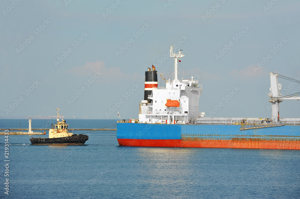 Fototapeta premium Tugboat assisting bulk cargo ship