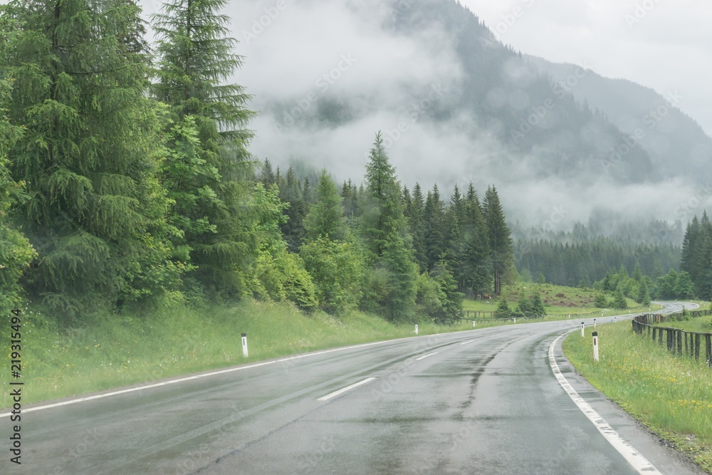 Fototapeta premium Mokra nawierzchnia drogi i krople deszczu na przedniej szybie samochodu