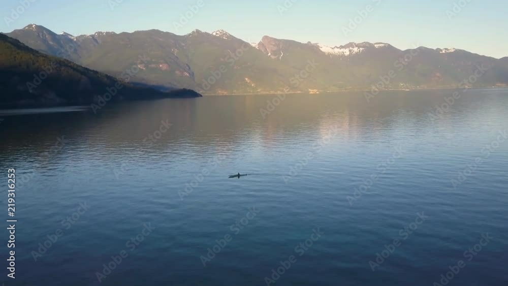 Aerial shot of kayak paddling on lake in mountains while sunset light Aerial shot of kayak paddling on lake in mountains while sunset light