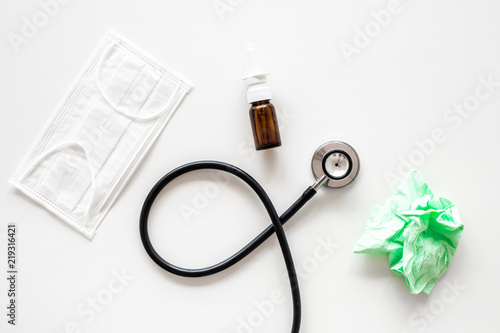 Flu drops. Running nose concept. Wrinkled napkin near stethoscope and face mask on white background top view