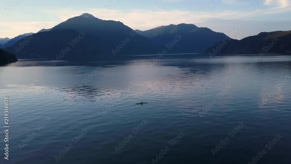 Aerial shot of kayak paddling on lake in mountains while sunset light Aerial shot of kayak paddling on lake in mountains while sunset light