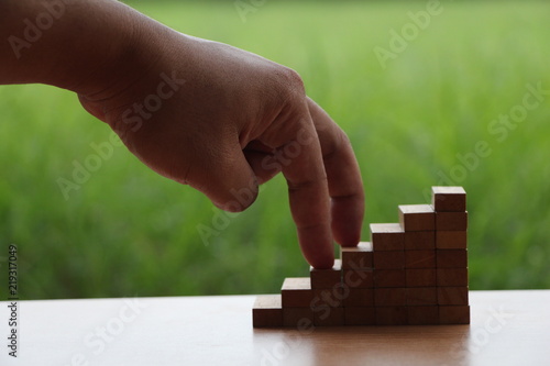 Hand walk on wood block stacking as step stair.business growth to success