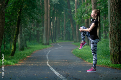 Beautiful attractive young woman stretching in the park and listen music