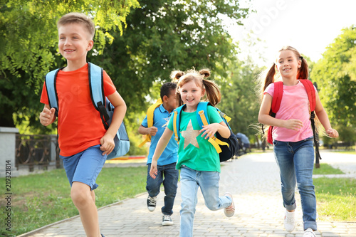Fotografie Cute little children with backpacks running outdoors