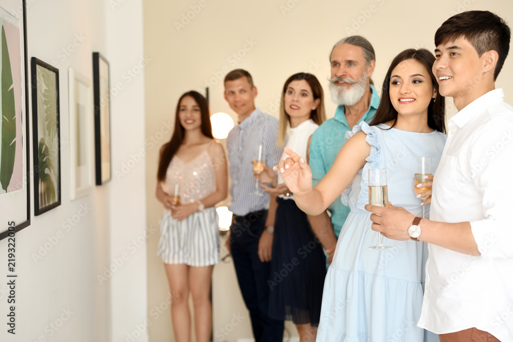 Group of people with glasses of champagne at exhibition in art gallery