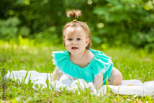 little girl in a dress sitting on a juicy green grass