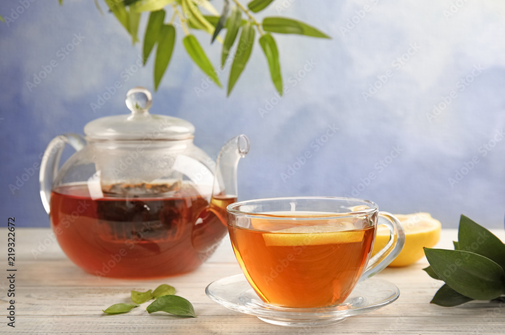 Glass cup and teapot with black tea on wooden table Glass cup and teapot with black tea on wooden table
