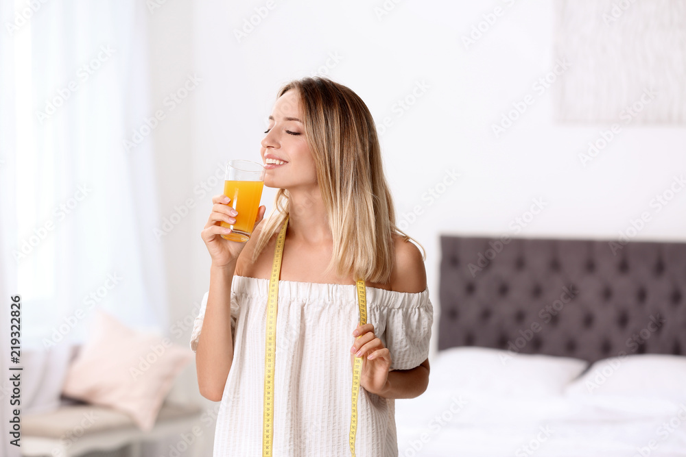 Happy slim woman with measuring tape and glass of juice at home. Positive weight loss diet results Happy slim woman with measuring tape and glass of juice at home. Positive weight loss diet results