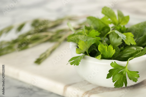 Bowl with fresh herbs on table, closeup