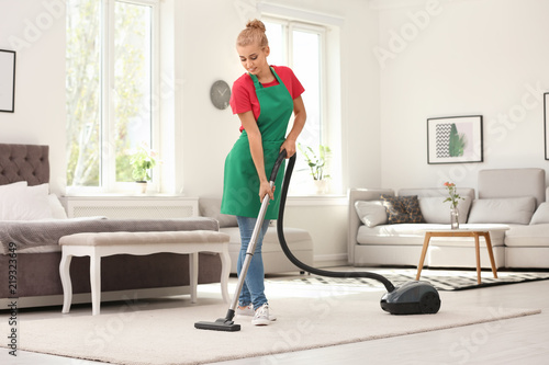 Woman removing dirt from carpet with vacuum cleaner indoors