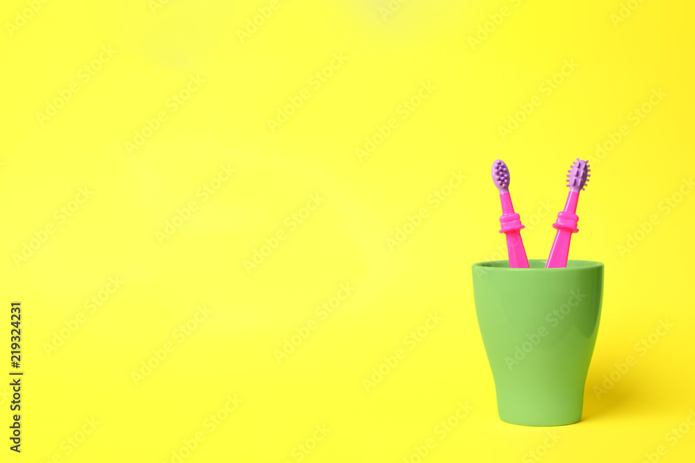 Baby toothbrushes in holder and space for text on color background