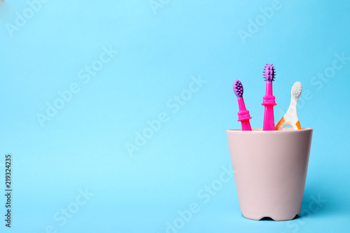 Baby toothbrushes in holder and space for text on color background