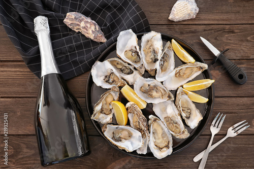 Fresh oysters with cut juicy lemon served on table, flat lay