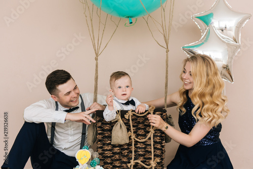 Happy young family celebrates the first birthday of the child. The baby is 1 year old. The concept of a children's party with balloons photo