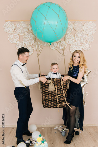 Happy young family celebrates the first birthday of the child. The baby is 1 year old. The concept of a children's party with balloons photo