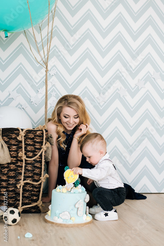 A cute baby is playing with his young mom on his first birthday. The concept of a children's party with balloons photo