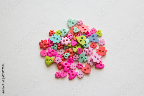Mixed coloured bright buttons. Colored buttons in the shape of heart. Button plastic colorful on white background and copy space. Beautiful color buttons. Sewing buttons. Many color plastic.
