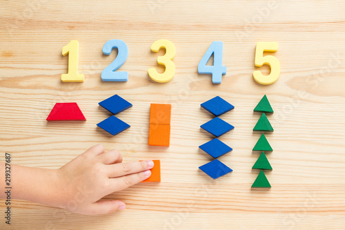 The child is studying the numbers and the account. Arranges the colored blocks to the desired numbers. Mathematics for children photo