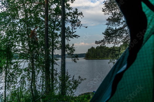 The quiet wild forest on the shore of the Saimaa lake in the Kolovesi National Park in Finland seen from a tent photo