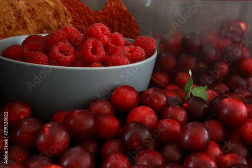 Raspberries and plums on a black table. Berries and fruit. 