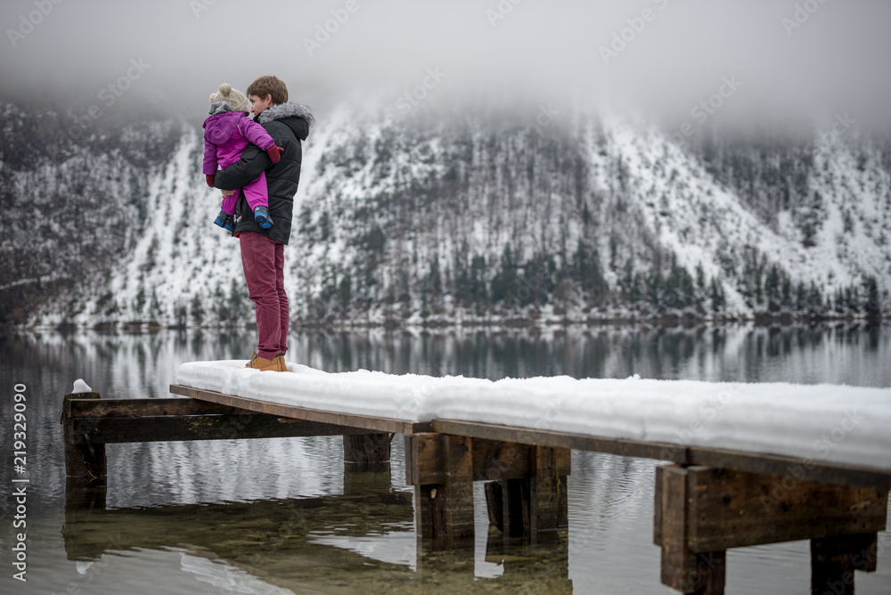 Father holding his baby daughter standing on a snowy pier