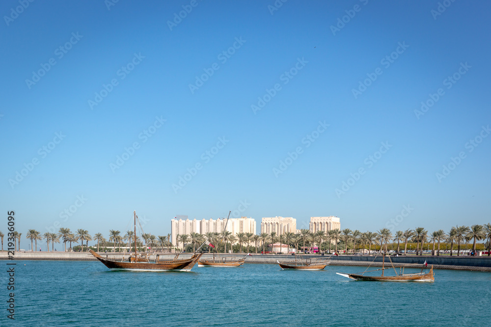 Traditional boat in a blue water sea with some buildings in the background in a blue sky day in Doha, Qatar