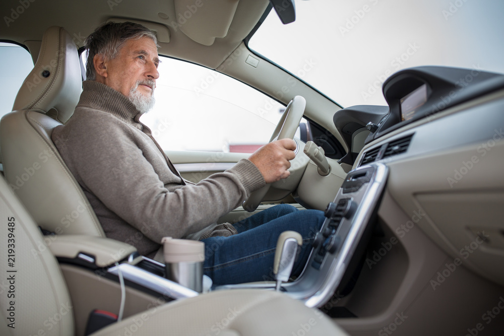 Senior man driving his modern car, going in reverse, watching out not to hit anything or anyone (color toned image; shallow DOF) Senior man driving his modern car, going in reverse, watching out not to hit anything or anyone (color toned image; shallow DOF)