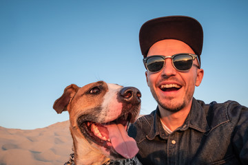 Funny best friends concept: human taking a selfie with dog. Happy young male person makes self portrait with his dog outdoors