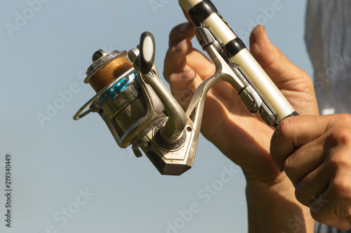 Fisherman with a fishing rod on the river bank. A fisherman is fishing. Fish, rotating coil. - The concept of rural recreation. Article about fishing.