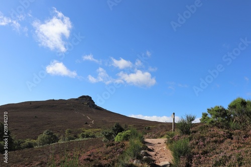 Mountain path under blue sky with fluffy white clouds