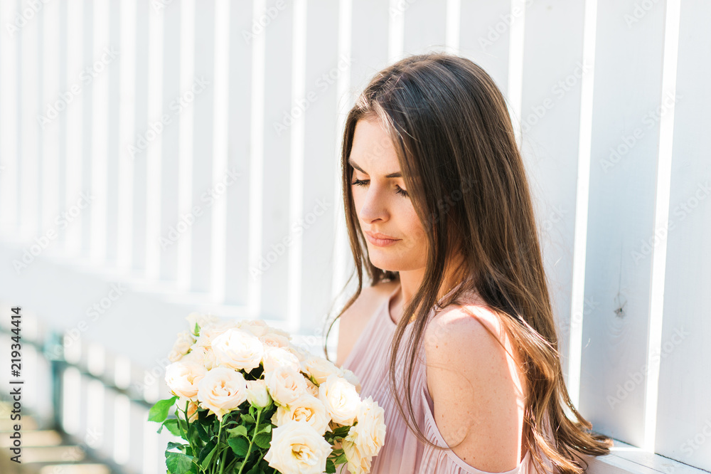 Happy beautiful woman with soft white roses, wearing blush cold shoulder blouse Happy beautiful woman with soft white roses, wearing blush cold shoulder blouse