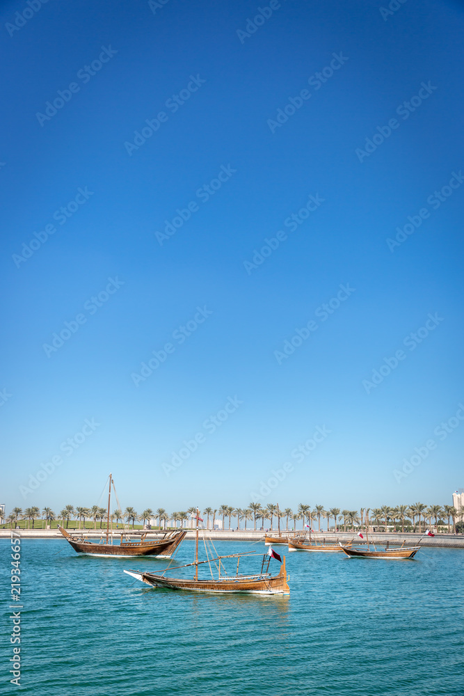 Traditional boat in a blue water sea with some buildings in the background in a blue sky day in Doha, Qatar