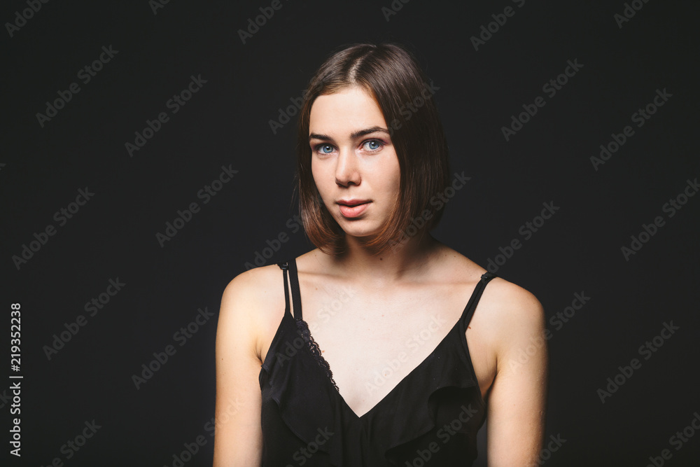 Fototapeta premium Portrait of a beautiful young Caucasian Caucasian woman 20 years old model with blue eyes natural make-up of hair on shoulder dancing hands posing on black isolated background in black lingerie