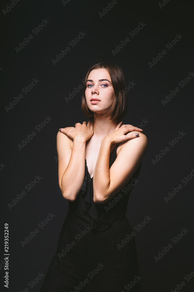 Portrait of a beautiful young Caucasian Caucasian woman 20 years old model with blue eyes natural make-up of hair on shoulder dancing hands posing on black isolated background in black lingerie