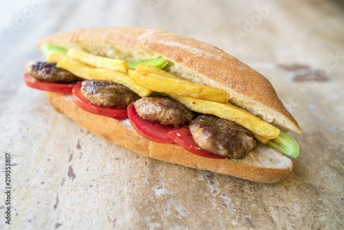 Homemade tasty and delicious spicy meatball in the sandwich with tomato, fried potatoes and green pepper. traditional turkish kebab