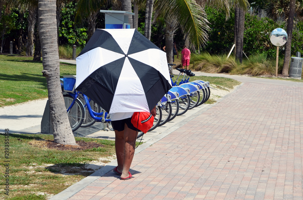 Teenaged boy strolling under a parasol on a very hot day at Southpointe Park  ,Miami Beach,Florida Stock Photo | Adobe Stock
