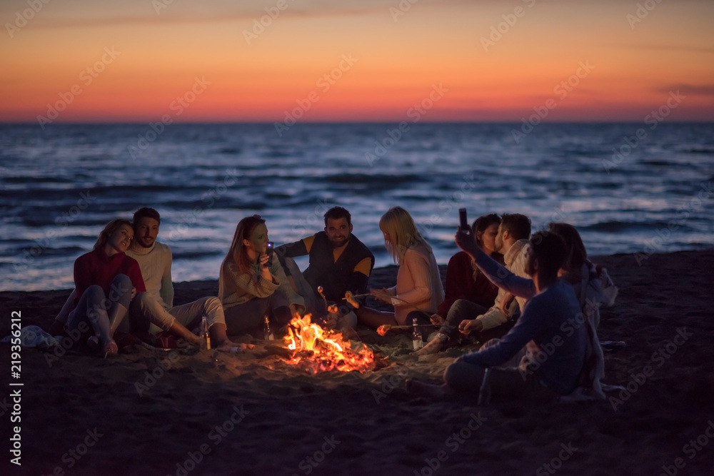 a group of friends enjoying bonfire on beach