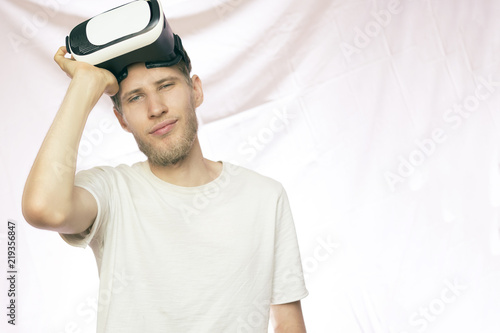 young bearded handsome smiling man holding the vr glasses isolated
