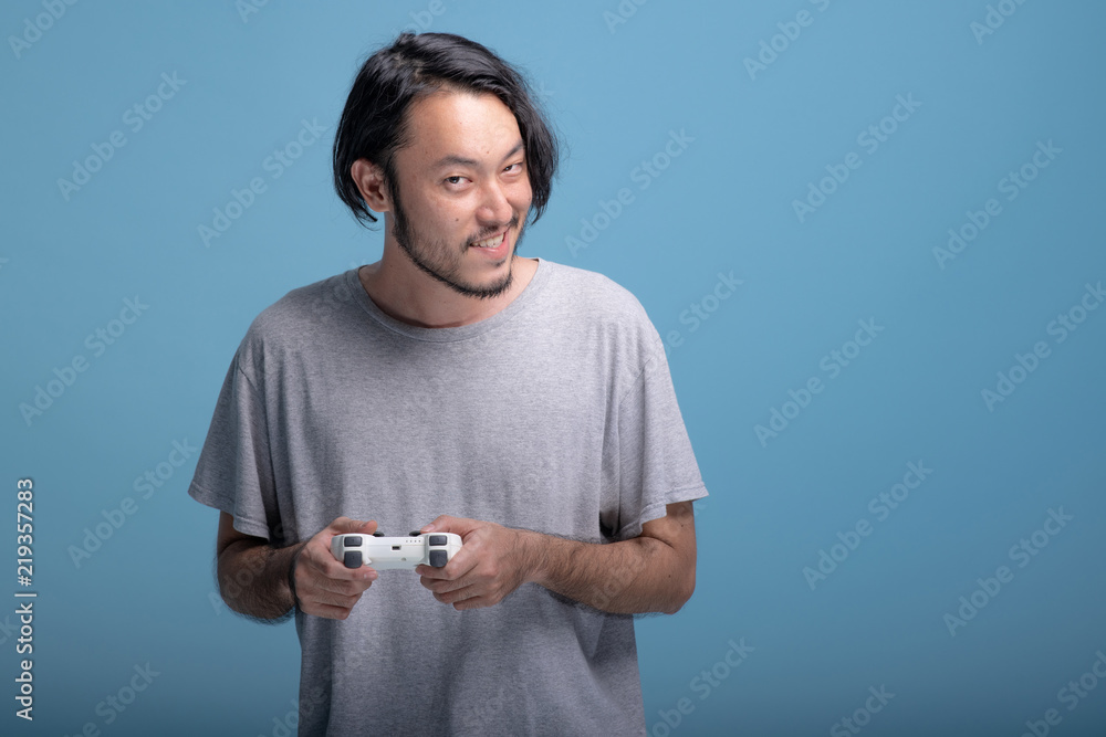 Young bearded man playing VR game in blue background. Young bearded man playing VR game in blue background.
