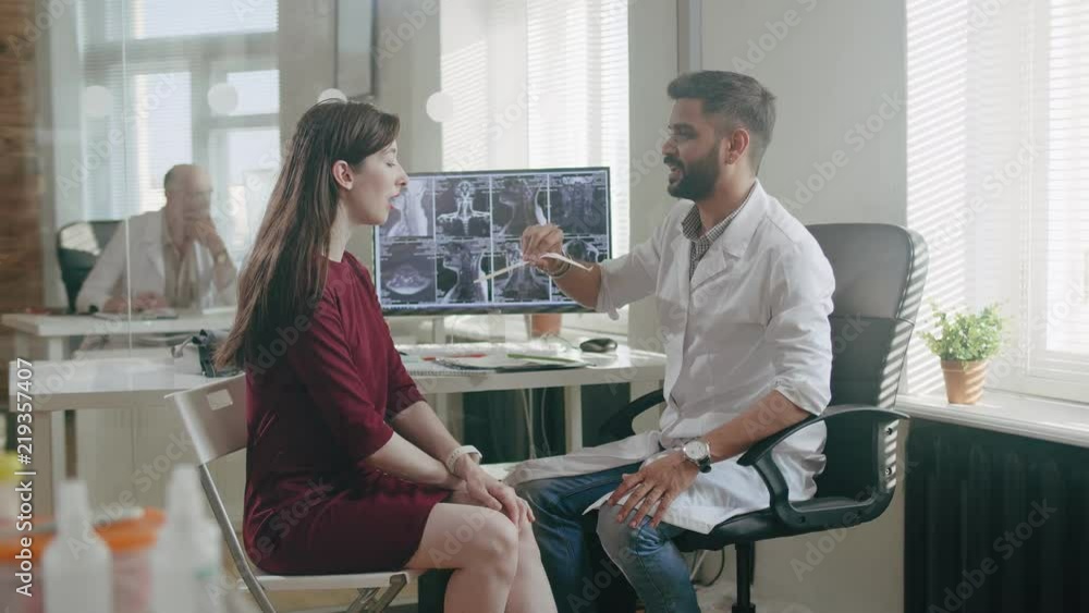 Doctor therapist examines throat of young woman Doctor therapist examines throat of young woman