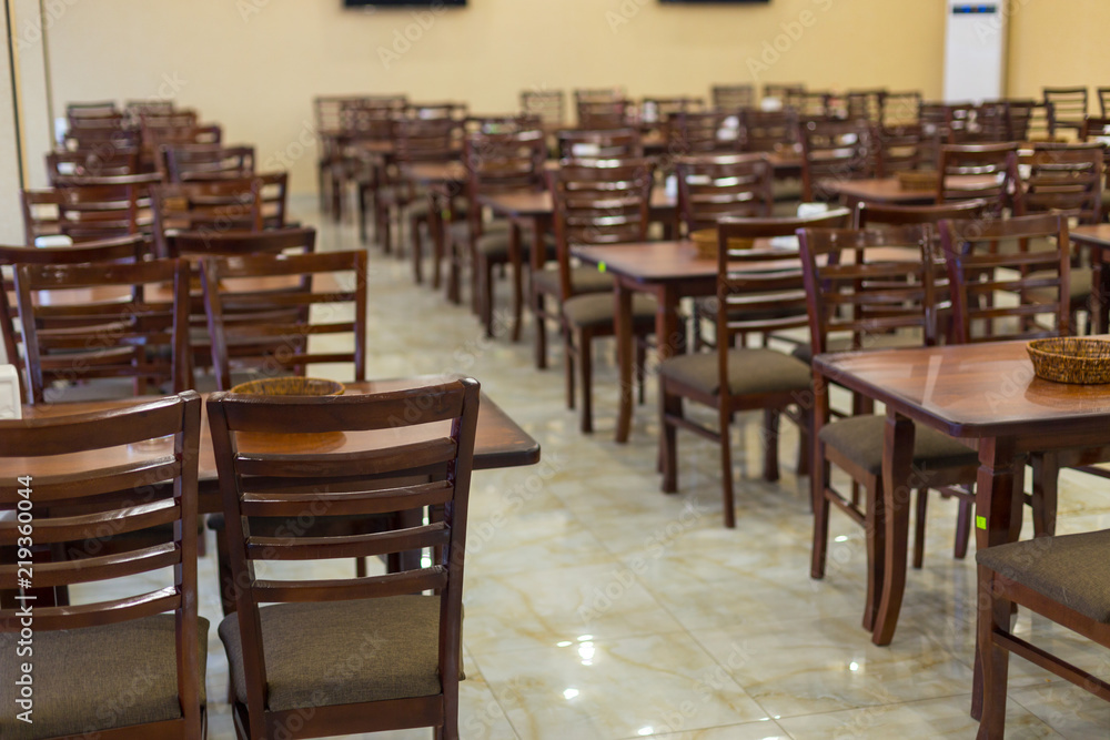 a lot of wooden, brown chairs in a cafe