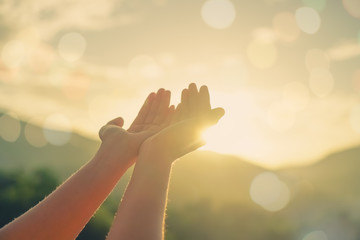 Woman hands place together like praying in front of nature green  background.