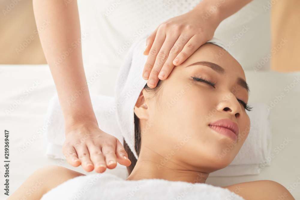 Pretty young Asian woman enjoying massage in spa salon